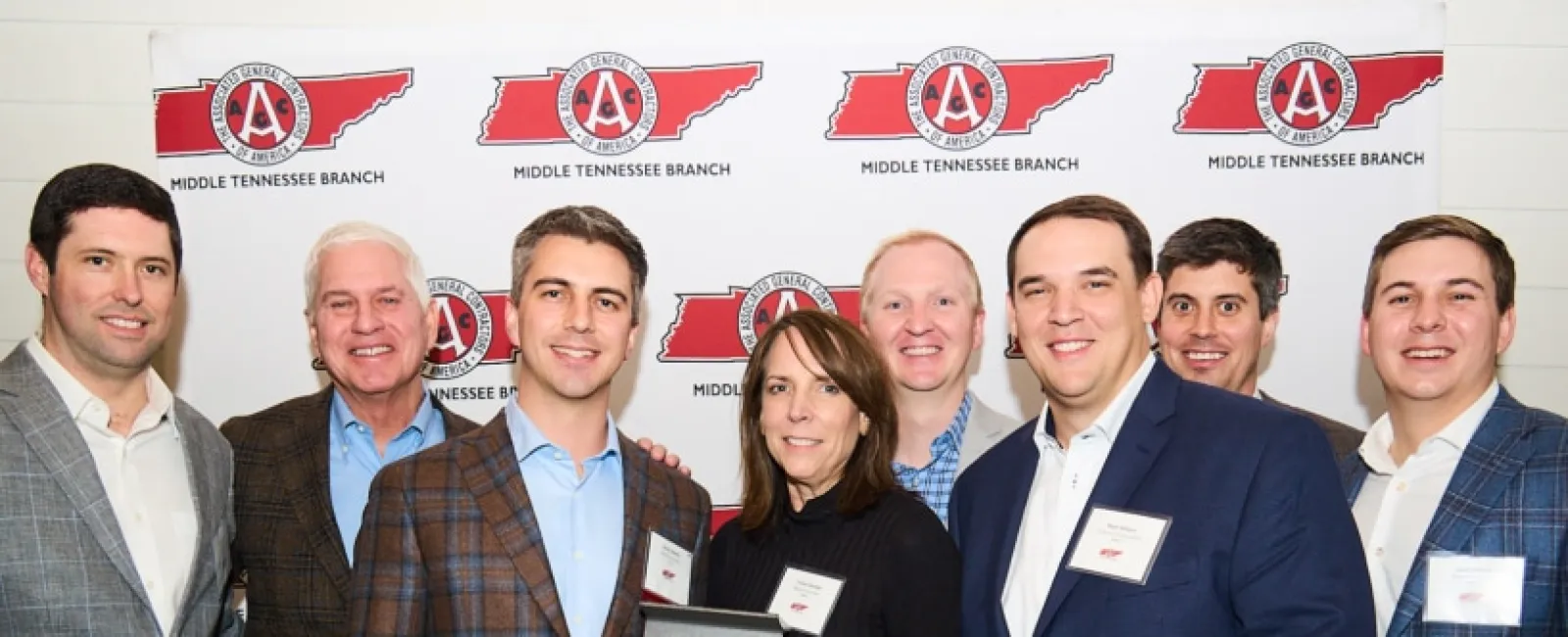 Group of eight people in business attire posing with an award plaque at Middle Tennessee Branch event.