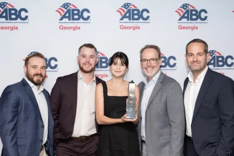 Five professionals pose with an award at the ABC Georgia event against a branded backdrop.