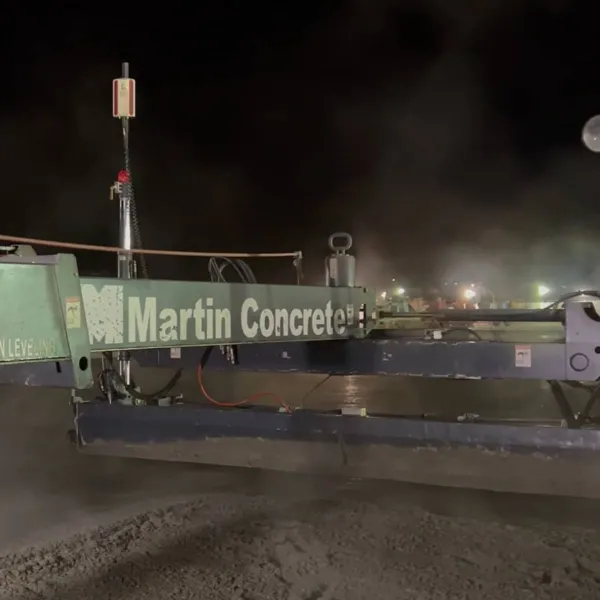 Nighttime concrete leveling using Martin Concrete equipment emitting mist from the wet surface.