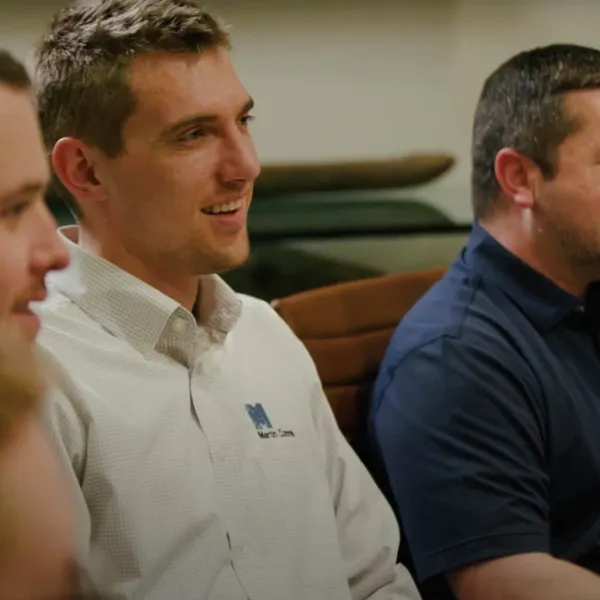 Four men sitting and smiling during a meeting in a casual office setting.
