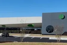 Thumbnail for Modern commercial building with gray and white exterior, circular windows, and a clear blue sky background.