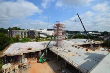 Thumbnail for Construction site showing a concrete building under development with cranes and scaffolding on a clear day.