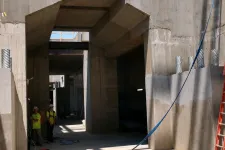 Thumbnail for Construction site with concrete walls, workers in safety gear, scaffolding, and an orange ladder under daylight