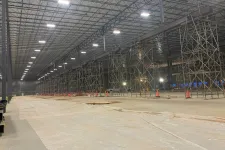 Thumbnail for Large industrial warehouse interior under construction with metal scaffolding and overhead lighting.