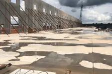 Thumbnail for Concrete wall structure under construction with supporting braces and wet concrete floor reflecting cloudy sky.