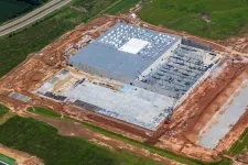 Thumbnail for Aerial view of a large industrial building under construction with steel frameworks and concrete flooring.