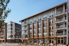 Thumbnail for Modern apartment complex with brick and glass exterior under clear blue sky in urban setting