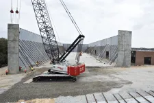 Thumbnail for Large crane and workers constructing a massive concrete structure at a construction site under cloudy sky