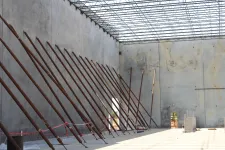 Thumbnail for Construction site with concrete walls supported by angled steel braces and a large open ceiling grid.