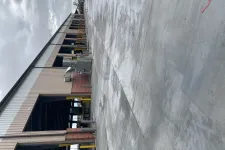 Thumbnail for Wet concrete loading dock area beside industrial warehouse building under cloudy sky