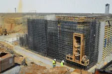 Thumbnail for Two construction workers inspect steel rebar framework for concrete wall at an industrial building site under construction.