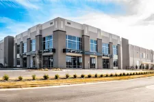 Thumbnail for Modern commercial warehouse building with large windows and clear blue sky in an industrial area.
