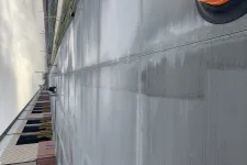 Thumbnail for Freshly poured concrete pavement next to industrial building under cloudy sky with orange traffic barrel.