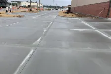 Thumbnail for Freshly poured concrete pavement in an industrial area near a brick building and construction site.
