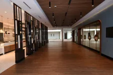 Thumbnail for Spacious modern hallway with wooden flooring, slatted ceiling, decorative black partitions, and glass wall accents.