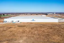 Thumbnail for Large white Georgia-Pacific factory building in a rural area under clear blue sky with surrounding farmland.