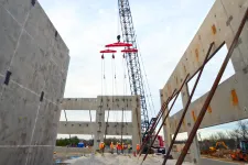 Thumbnail for Construction workers assemble concrete walls with a large crane on an open building site.
