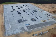 Thumbnail for Aerial view of a large concrete foundation with stacked construction materials at a building site.
