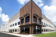 Thumbnail for Modern industrial building with wooden panels and large windows under a blue sky with clouds