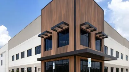 Modern commercial building with wood paneling corner, large glass windows, and blue sky background under bright daylight