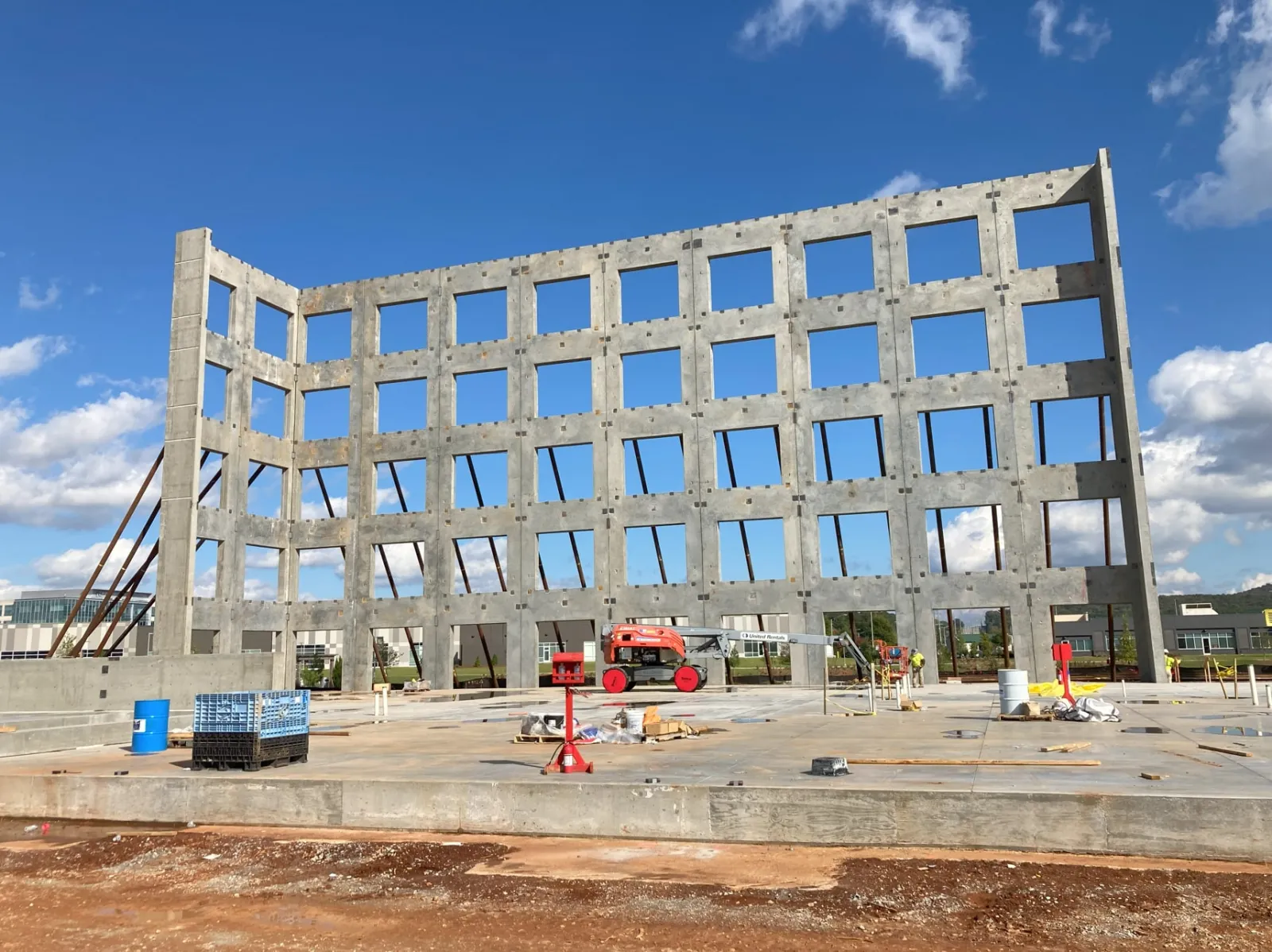 Construction site with a large concrete frame structure and a red construction lift under a blue sky