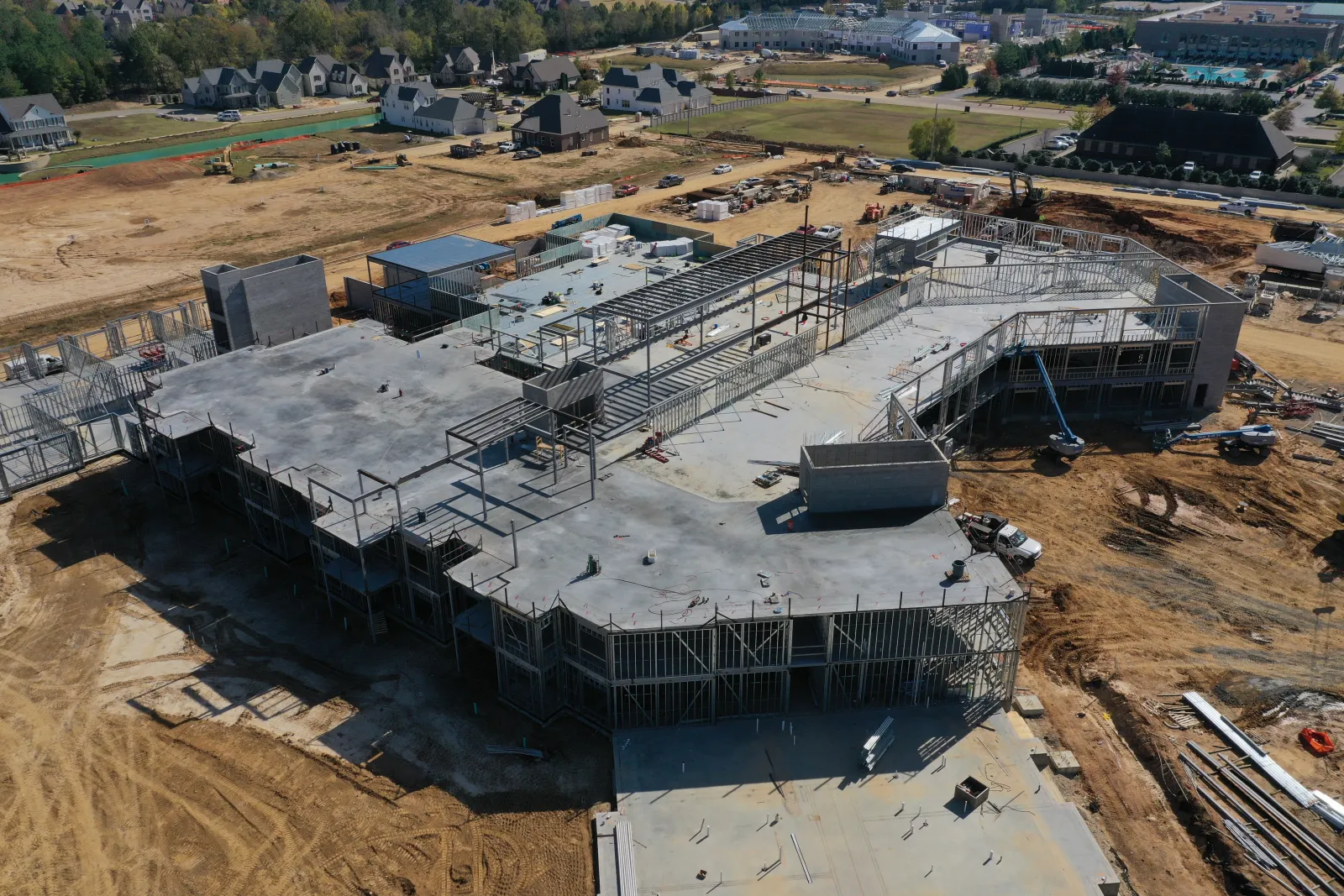 Aerial view of a large commercial building under construction with steel framework and concrete slabs.
