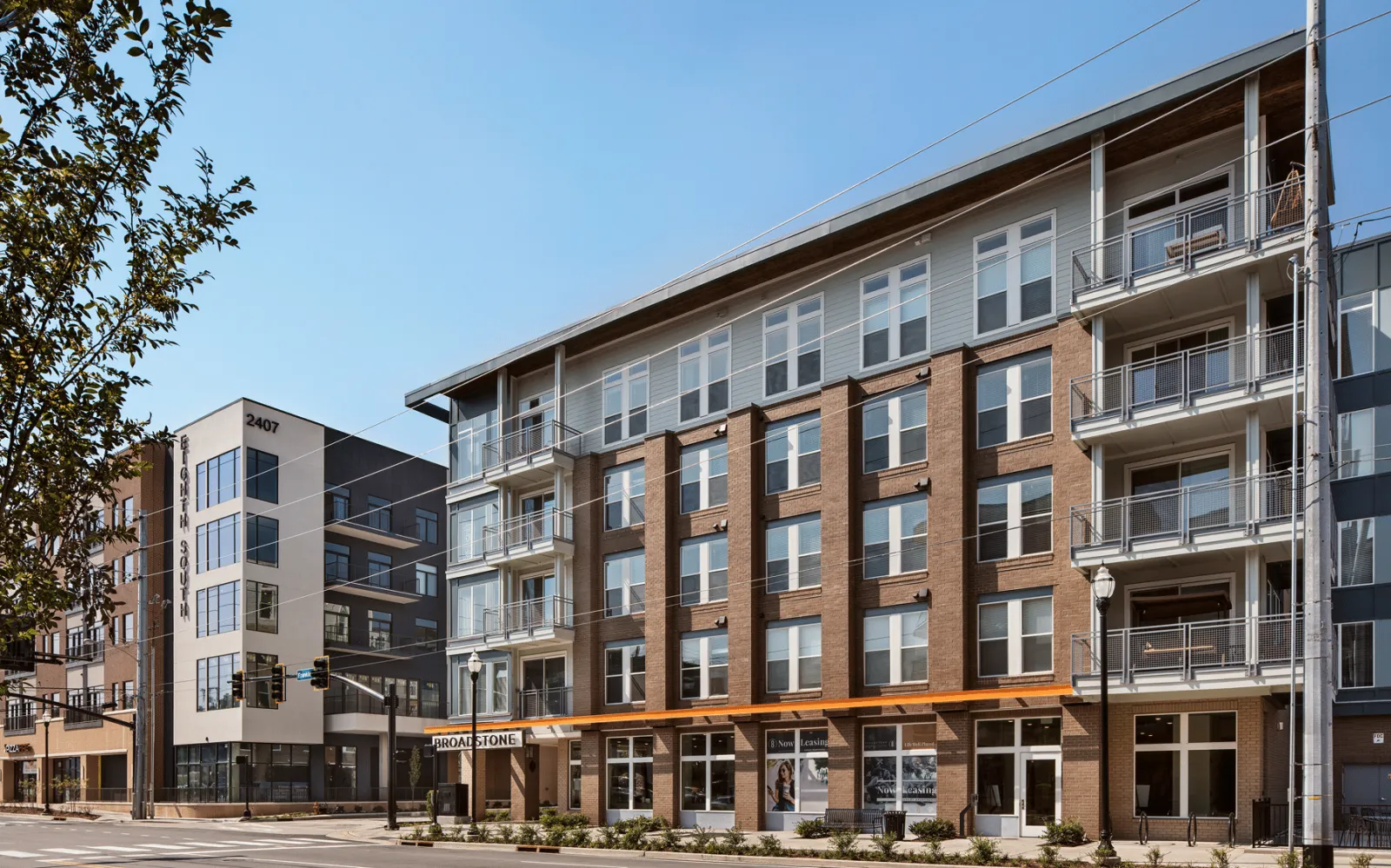 Modern apartment complex with brick and glass exterior under clear blue sky in urban setting