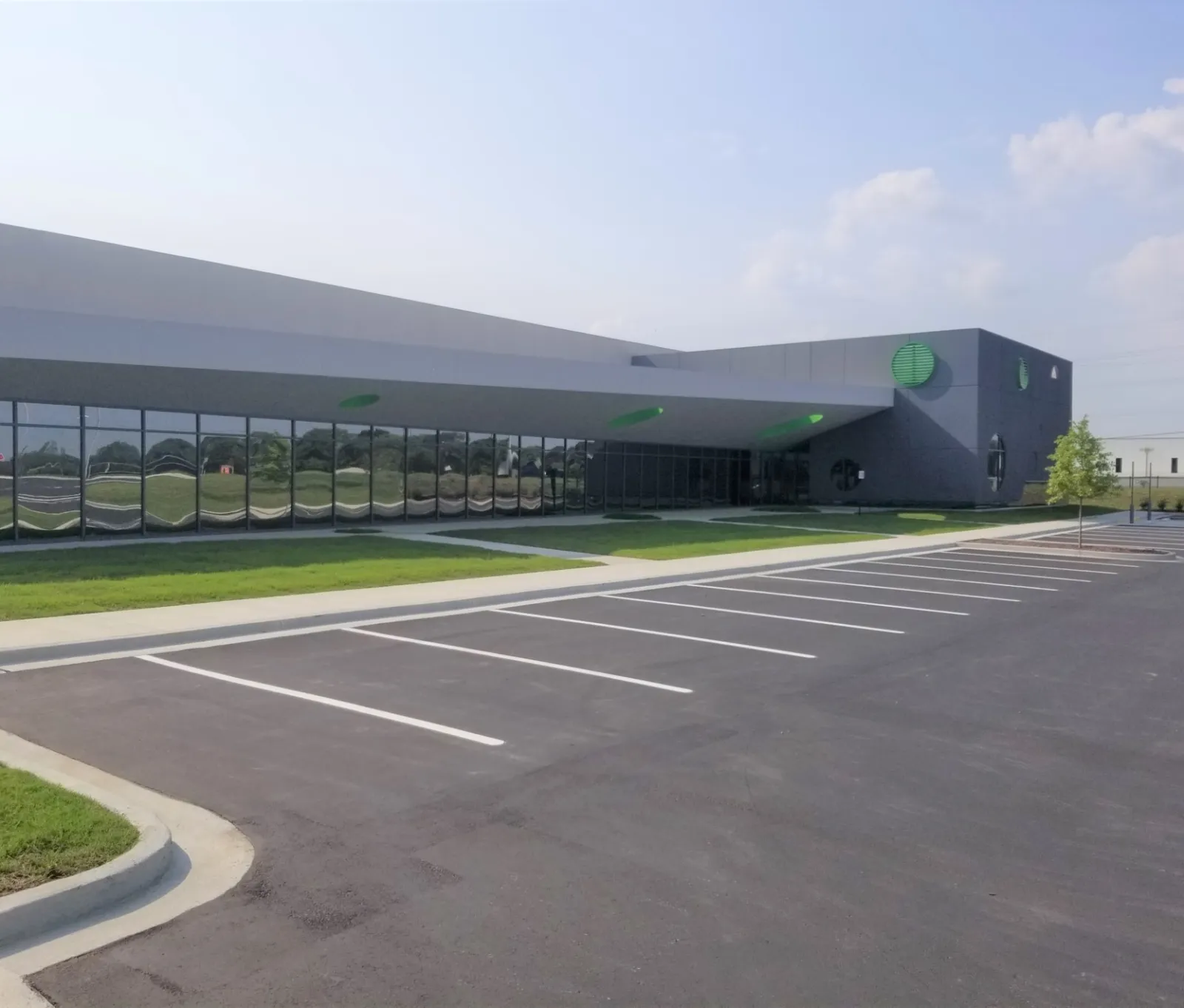 Modern commercial building with large windows and empty parking lot on a clear sunny day