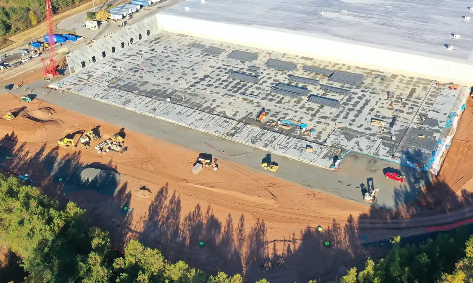 Aerial view of a construction site with earthmoving equipment and a large foundation being prepared for building.